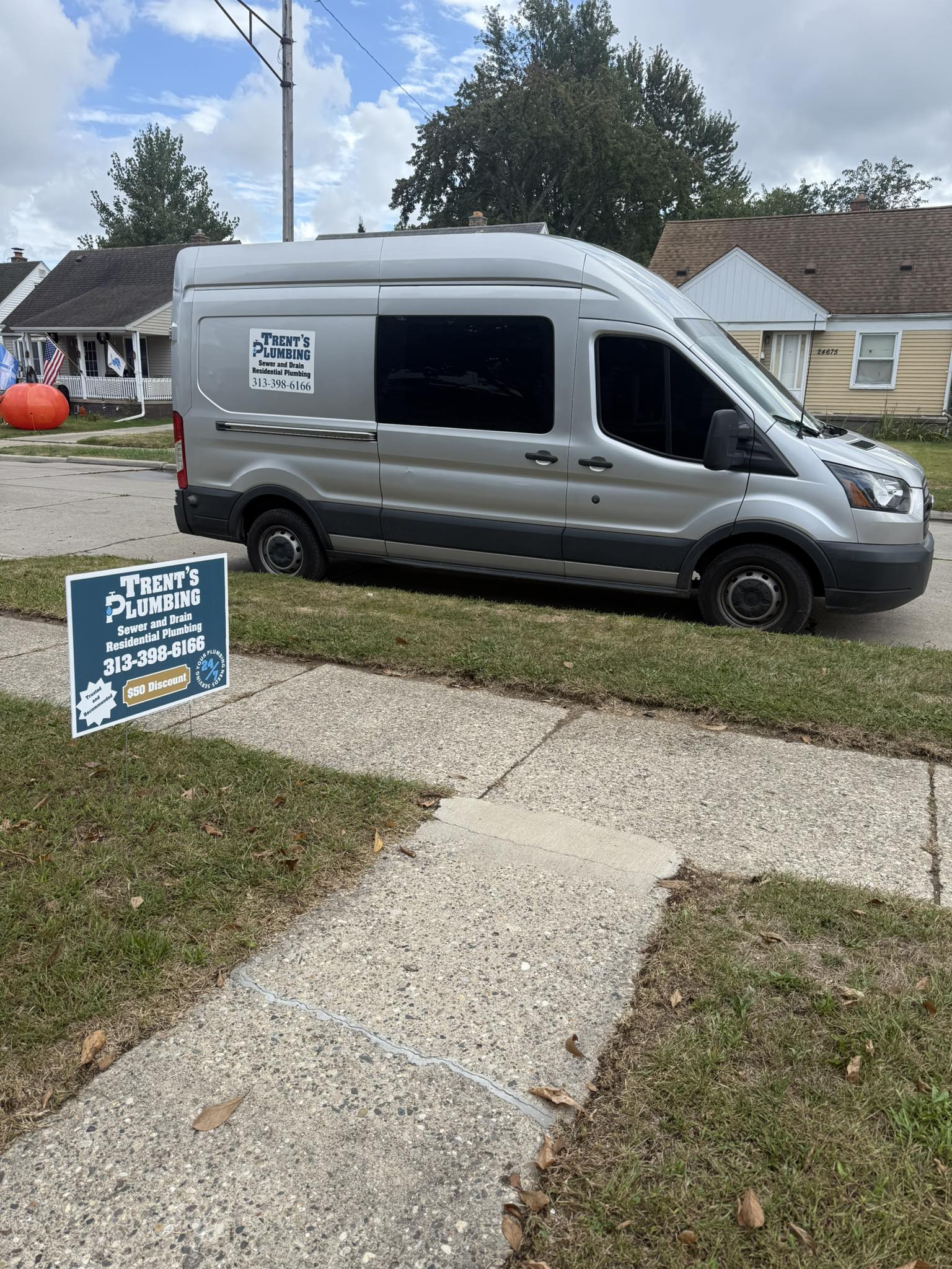 Trent's Plumbing branded van and yard sign on job site